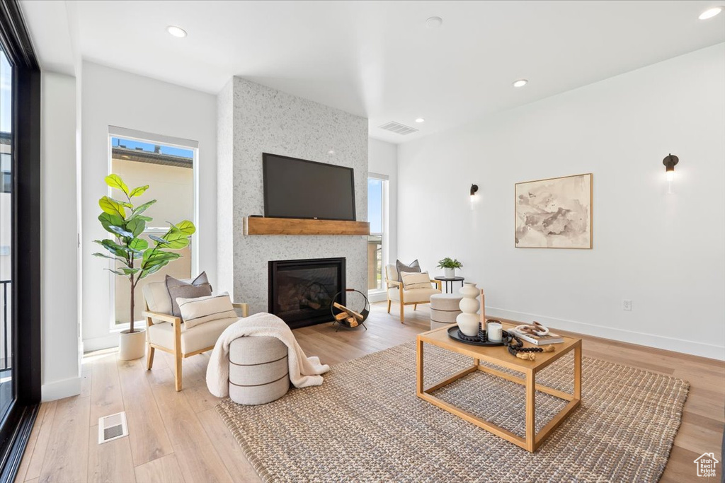 Living room with light wood-type flooring, a fireplace, and recessed lighting
