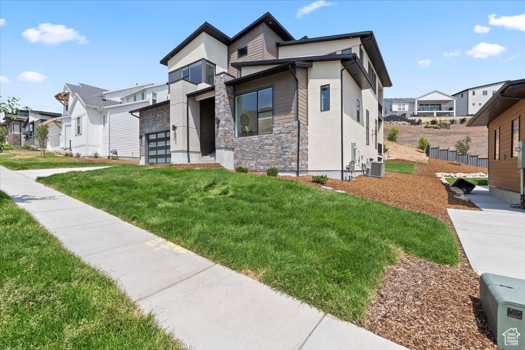 Contemporary home featuring stone siding, a residential view, a front yard, and stucco siding