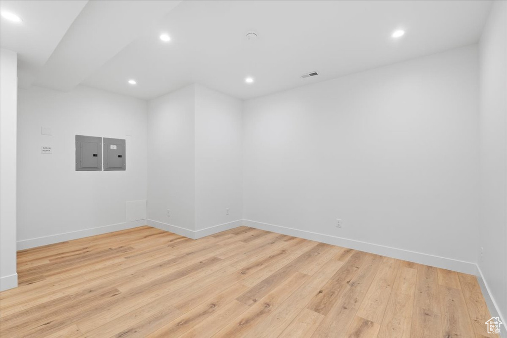 Empty room featuring electric panel, light wood finished floors, and recessed lighting