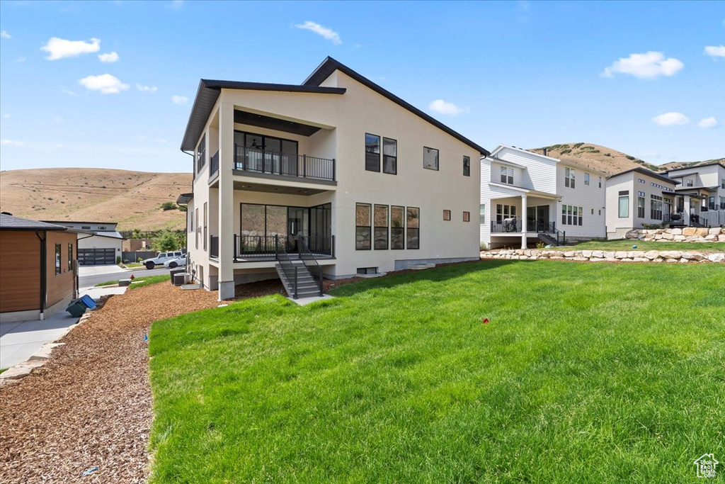 Back of property featuring a balcony, a yard, stucco siding, and a residential view