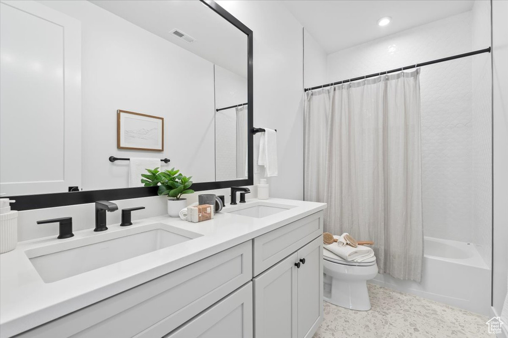 Bathroom with double vanity, shower / bathtub combination with curtain, and recessed lighting