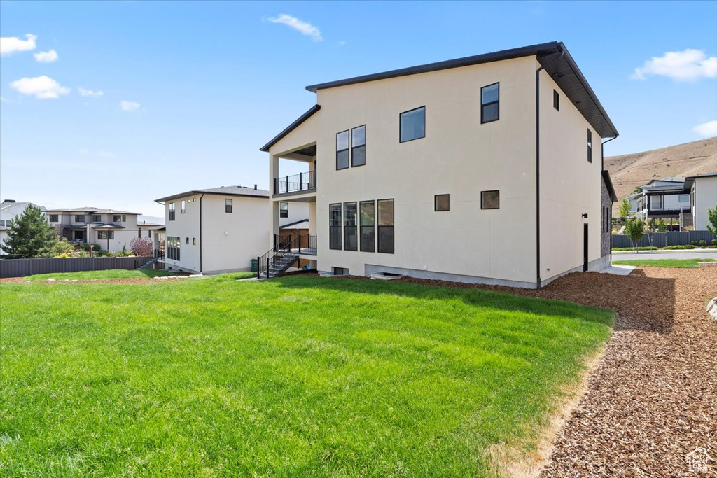 Back of house with a balcony, stucco siding, and a residential view