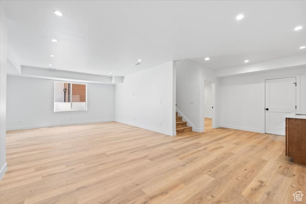Unfurnished living room with stairs, light wood-style flooring, and recessed lighting