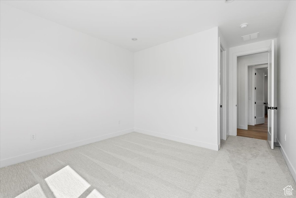 Empty room featuring light colored carpet and baseboards