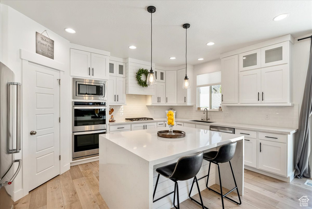 Kitchen featuring stainless steel appliances, light countertops, a center island, white cabinets, and recessed lighting
