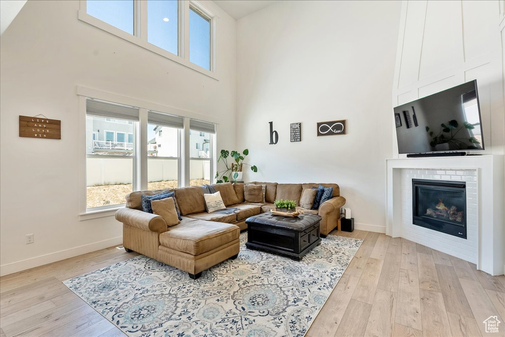 Living area featuring a high ceiling, a fireplace, healthy amount of natural light, and light wood-style flooring