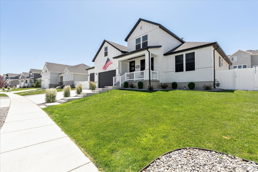 Modern farmhouse style home featuring covered porch, a residential view, board and batten siding, and a garage