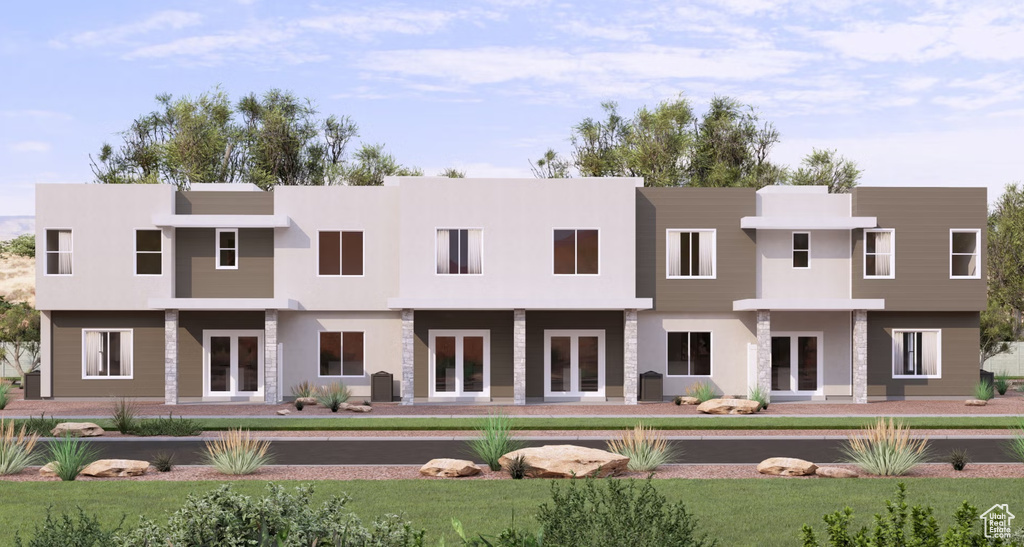Back of house featuring stucco siding and a lawn