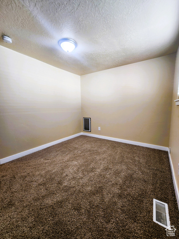 Spare room with a smoke detector, a textured ceiling, and carpet floors