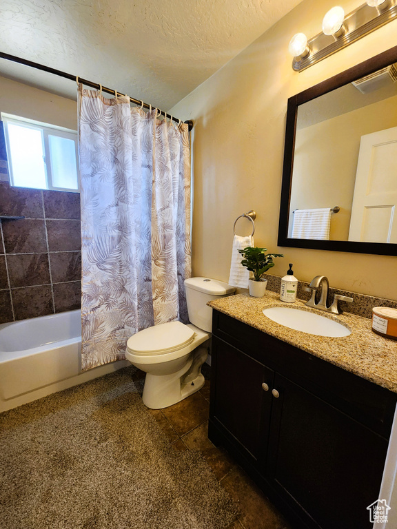 Bathroom with vanity, shower / tub combo with curtain, a textured ceiling, and tile patterned floors