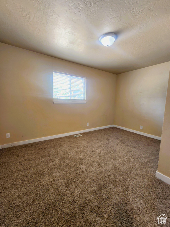Spare room featuring carpet flooring and a textured ceiling