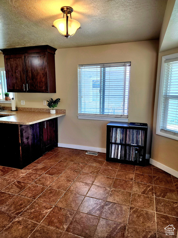 Kitchen with dark brown cabinets, a textured ceiling, and light countertops