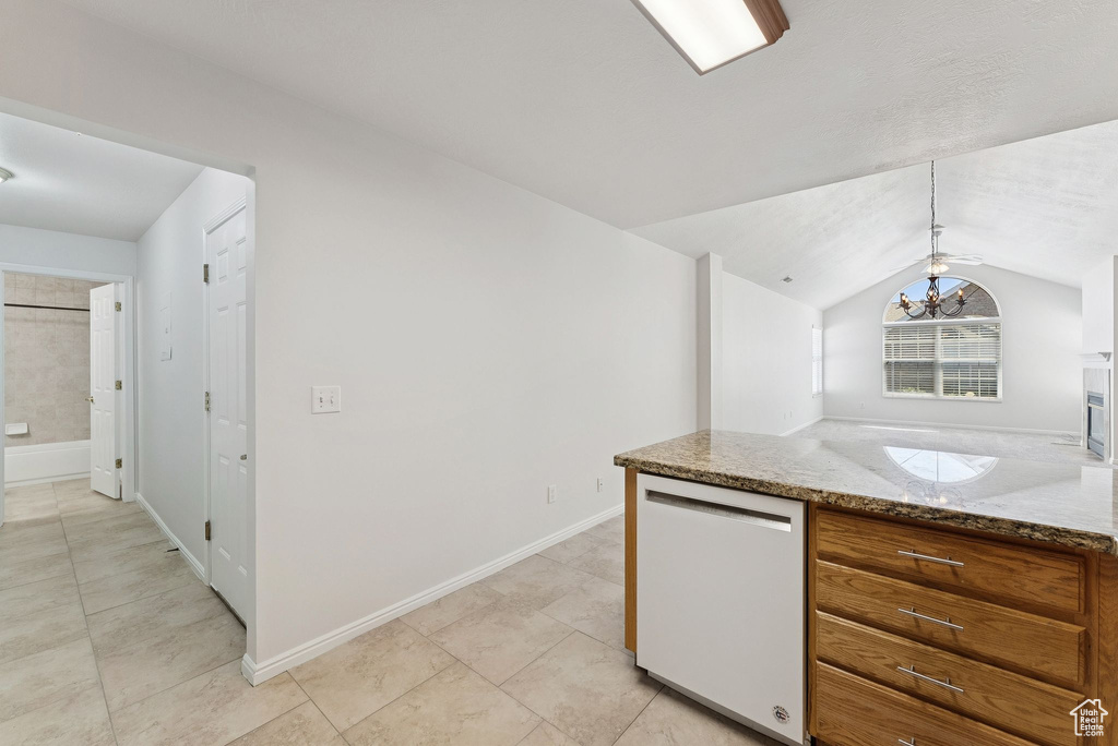 Kitchen featuring dishwasher, brown cabinets, lofted ceiling, a chandelier, and light tile patterned floors