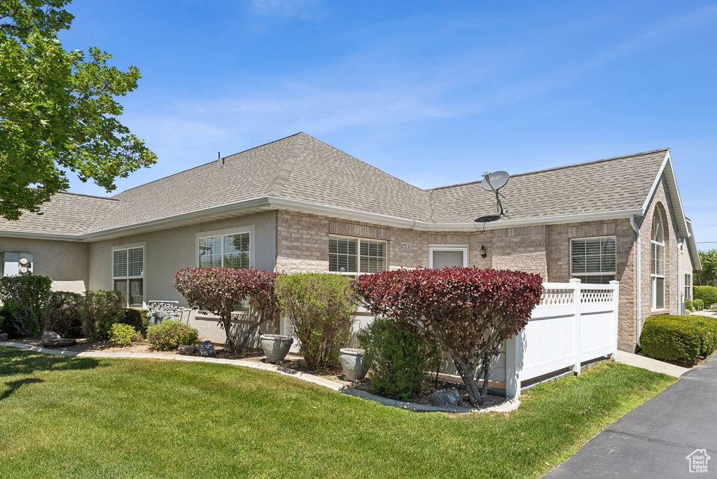 View of property exterior featuring a shingled roof, a lawn, and stucco siding