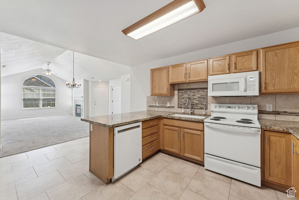 Kitchen featuring white appliances, light colored carpet, a chandelier, open floor plan, and vaulted ceiling