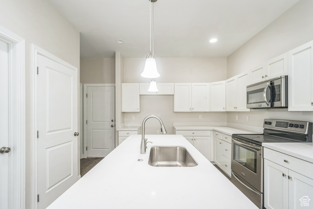 Kitchen with stainless steel appliances, white cabinetry, light countertops, pendant lighting, and recessed lighting
