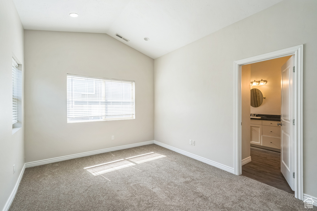 Unfurnished bedroom featuring carpet floors, lofted ceiling, and connected bathroom