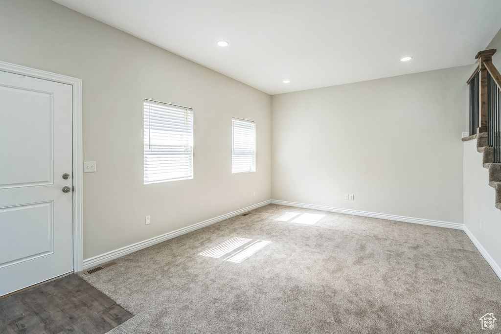 Unfurnished living room featuring stairs, carpet, and recessed lighting