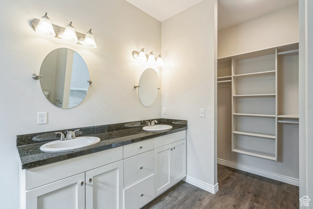 Bathroom with double vanity and wood finished floors