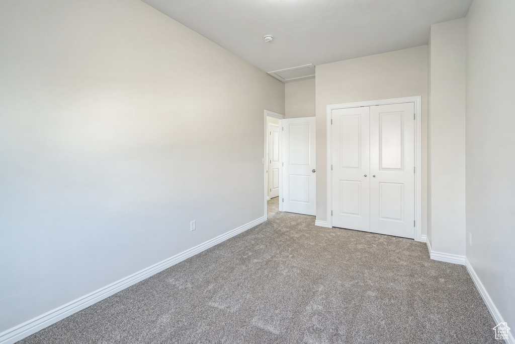 Unfurnished bedroom with carpet, a closet, and attic access