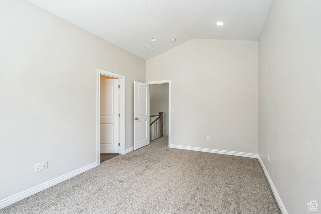 Unfurnished bedroom with carpet floors and lofted ceiling