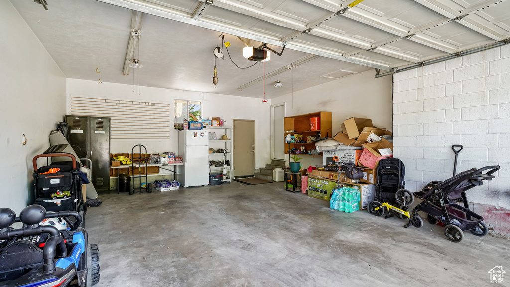 Garage with freestanding refrigerator and a garage door opener