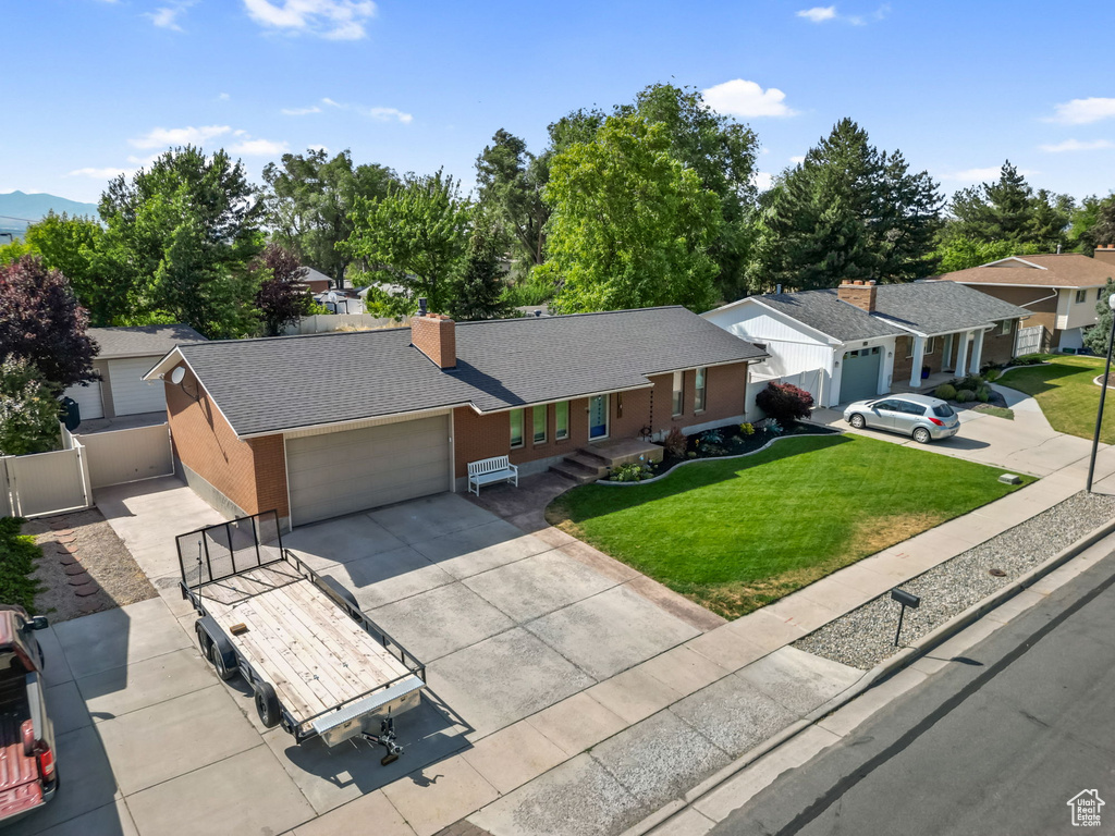 Single story home featuring an attached garage, driveway, a front yard, roof with shingles, and a residential view