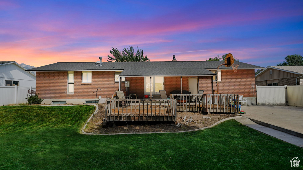 Rear view of house with a deck, brick siding, and a patio area