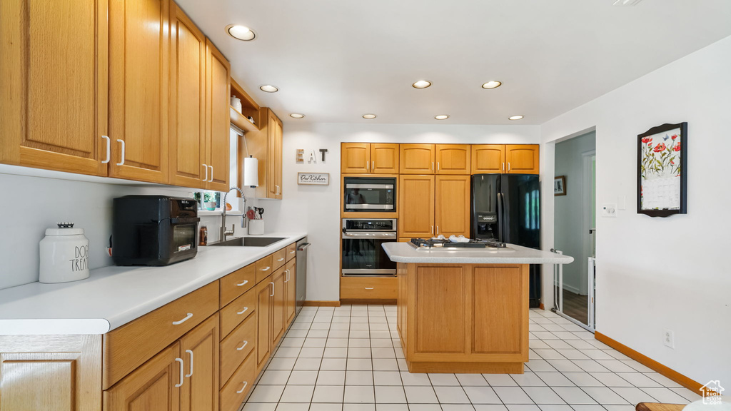 Kitchen featuring appliances with stainless steel finishes, light countertops, a center island, recessed lighting, and light tile patterned floors