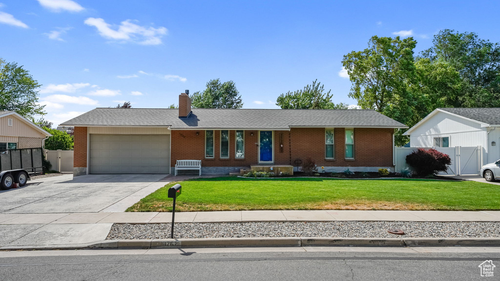 Single story home featuring brick siding, a garage, driveway, a chimney, and a gate