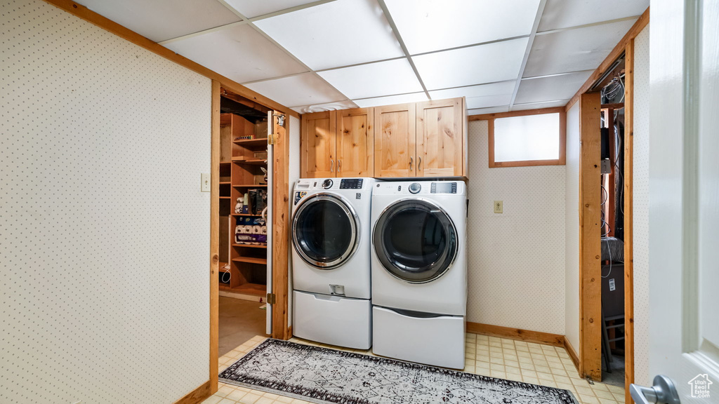 Laundry room with cabinet space, washing machine and dryer, and wallpapered walls