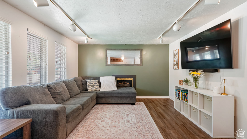 Living room with rail lighting, wood finished floors, a textured ceiling, and a fireplace