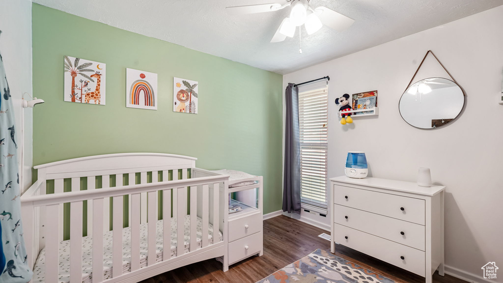 Bedroom with a nursery area, dark wood-type flooring, and multiple windows