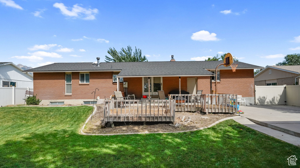 Rear view of property featuring a deck, a patio, and brick siding