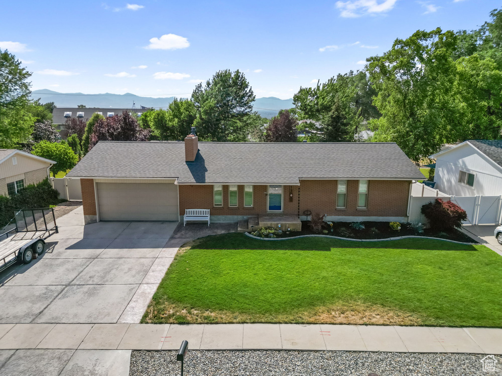 Ranch-style house with a mountain view, an attached garage, driveway, a chimney, and brick siding