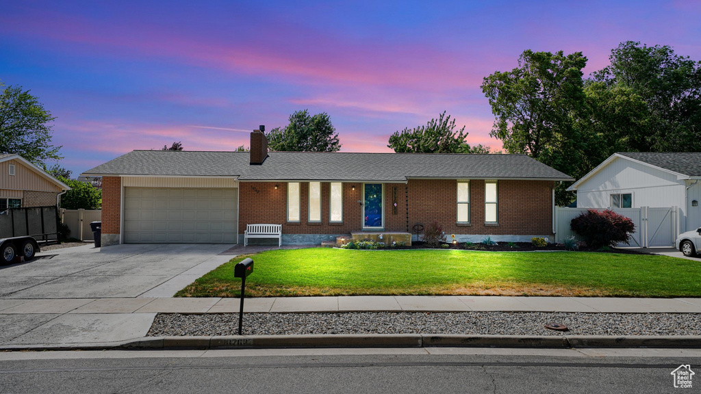 Single story home featuring a garage, driveway, brick siding, and a chimney