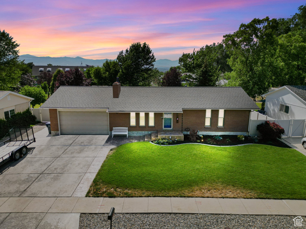 Single story home featuring driveway, a garage, a mountain view, a chimney, and brick siding