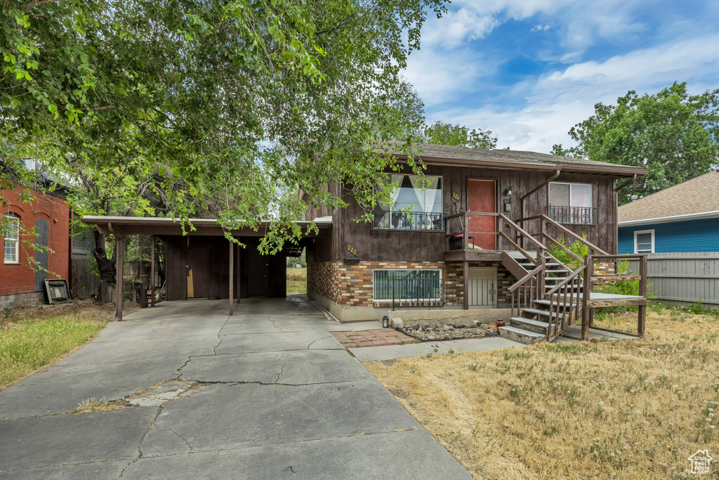 View of front facade with driveway, stairway, and a carport