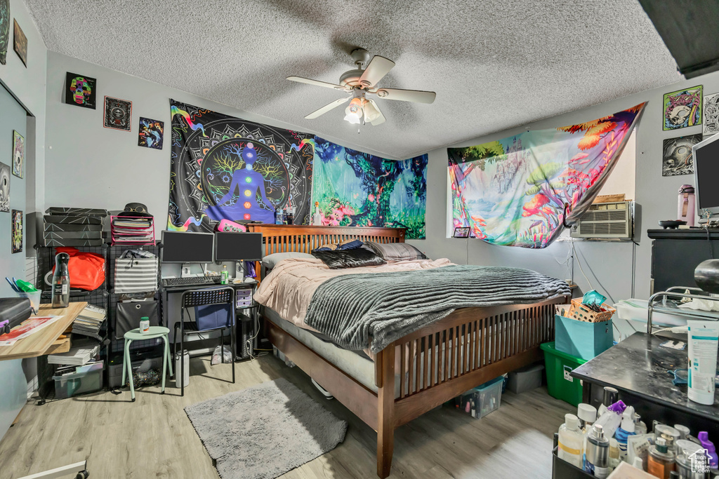 Bedroom featuring a textured ceiling, wood finished floors, cooling unit, and ceiling fan