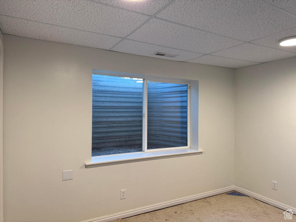 Unfurnished room featuring carpet and a paneled ceiling