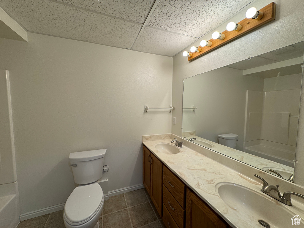 Bathroom with double vanity, shower / tub combination, tile patterned floors, and a paneled ceiling