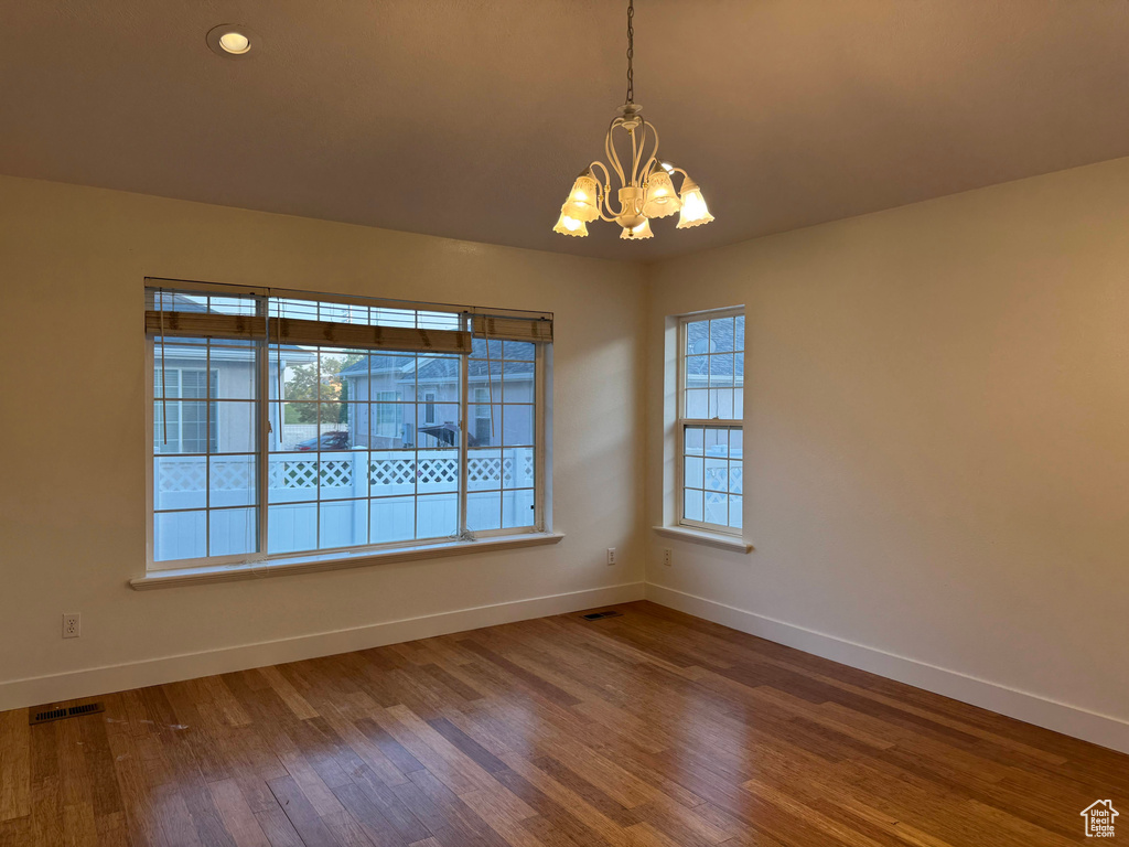 Unfurnished room featuring a chandelier and wood finished floors
