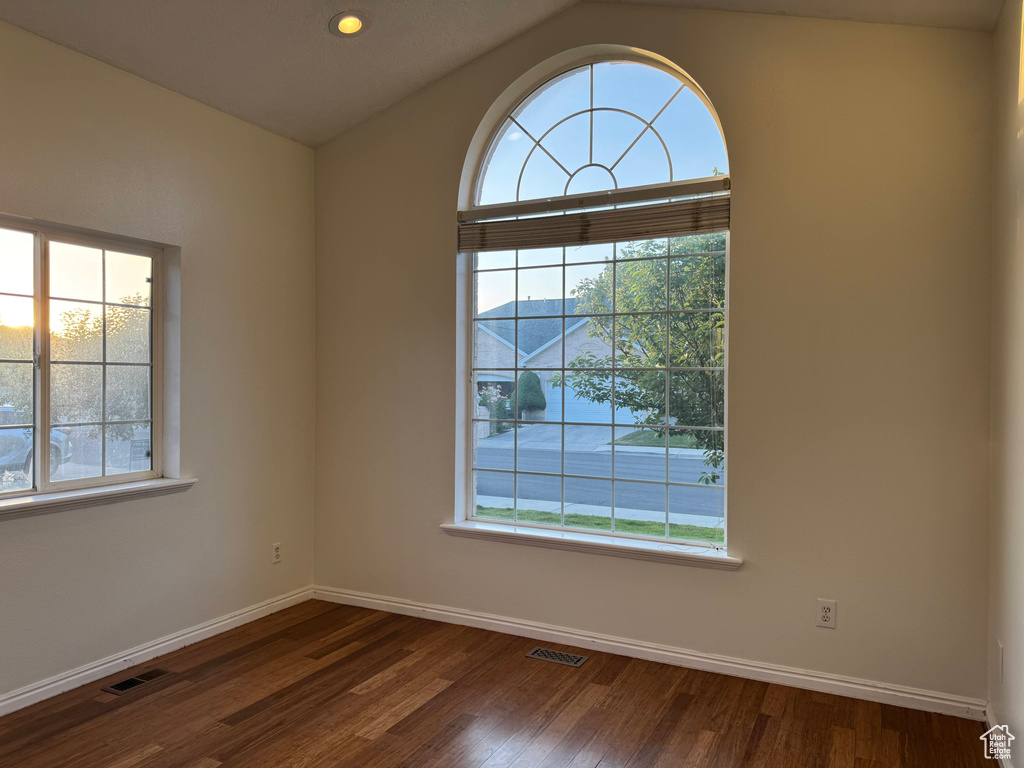 Spare room featuring plenty of natural light, dark wood-style flooring, vaulted ceiling, and recessed lighting