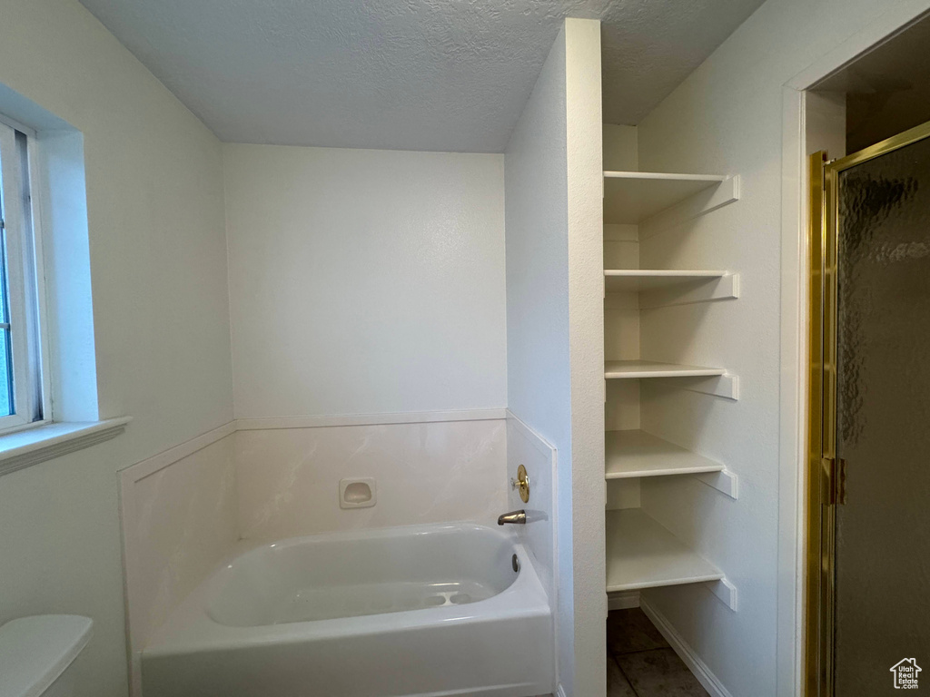 Bathroom featuring a bath, a shower stall, a textured ceiling, and tile patterned floors