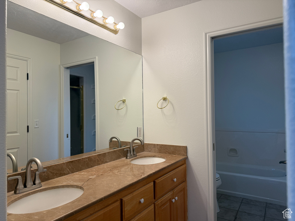 Bathroom featuring double vanity, tile patterned floors, and bathtub / shower combination