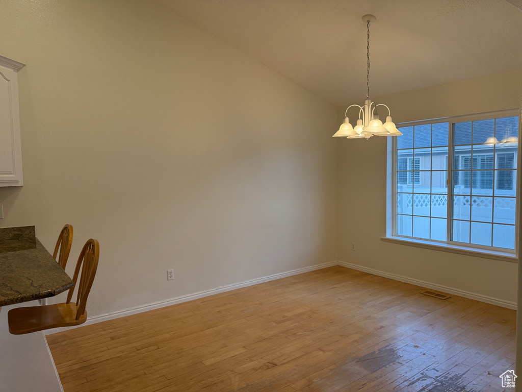 Unfurnished dining area featuring a chandelier and light wood-type flooring