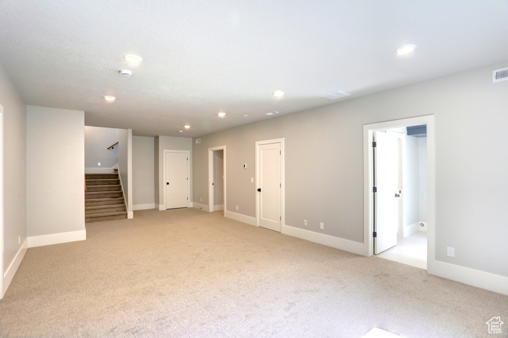 Unfurnished living room featuring light carpet, stairs, and recessed lighting