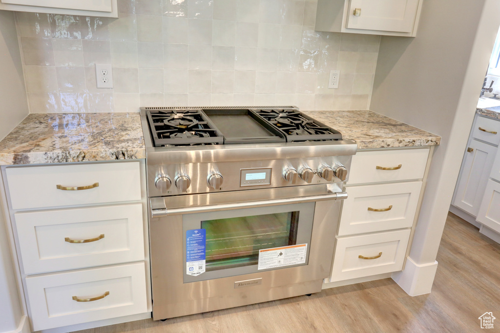 Kitchen featuring stainless steel stove, light wood-style flooring, and white cabinets
