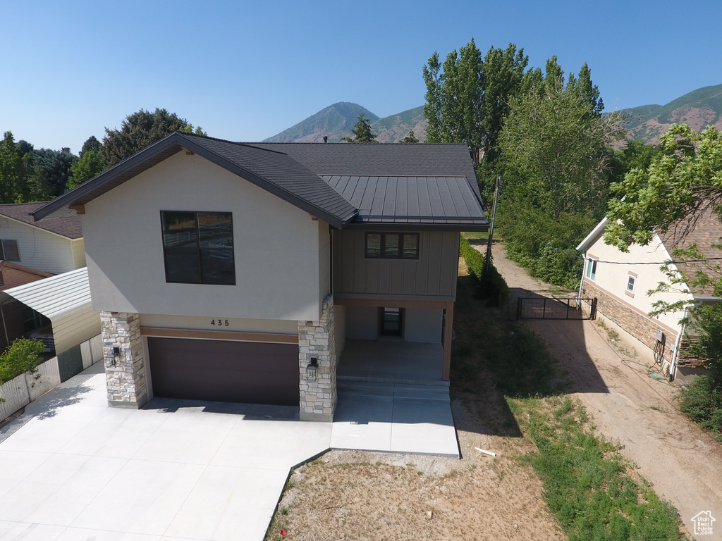 View of front facade with a garage, a standing seam roof, driveway, and a mountain view