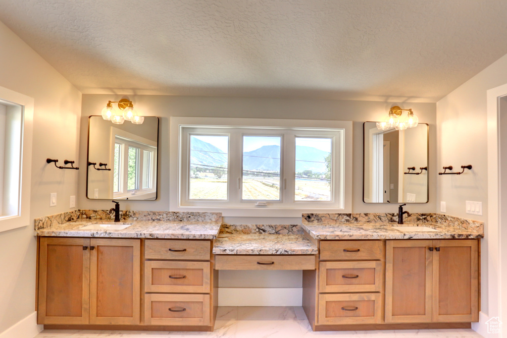 Full bathroom with marble look tiles, vanity, and a textured ceiling